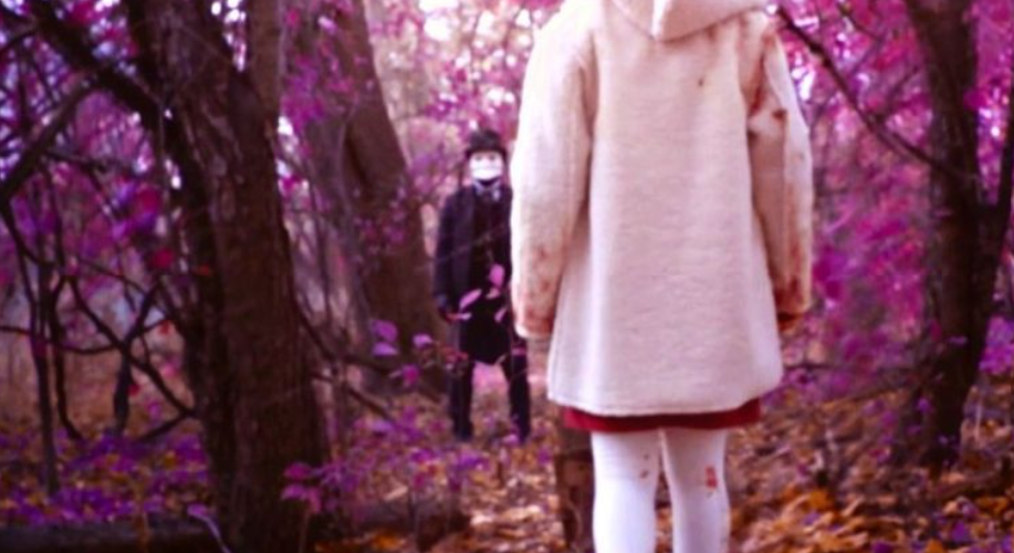 Slasher S4E7 a young woman in white walks through a purple woods towards what may be the killer