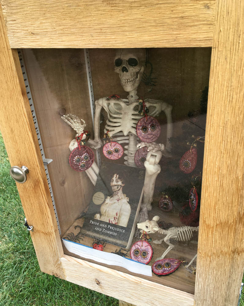Little library display with Pride and Prejudice and Zombies, faux skeleton and rat, black Christmas tree and lots and lots of eyes upon you keychain ornaments and plastic bugs