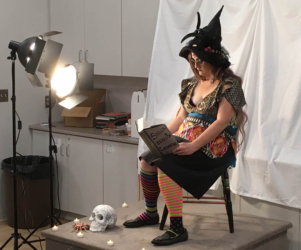 another image of the same witch reading for the figure modeling session, with lights and art cabinets in the background