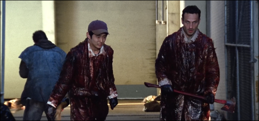 Screencap of The Walking Dead from The Last Drive-In with Joe Bob Briggs featuring Glenn Rhee (Steven Yeun) and Rick Grimes (Andrew Lincoln) covered in zombie gore in an alley