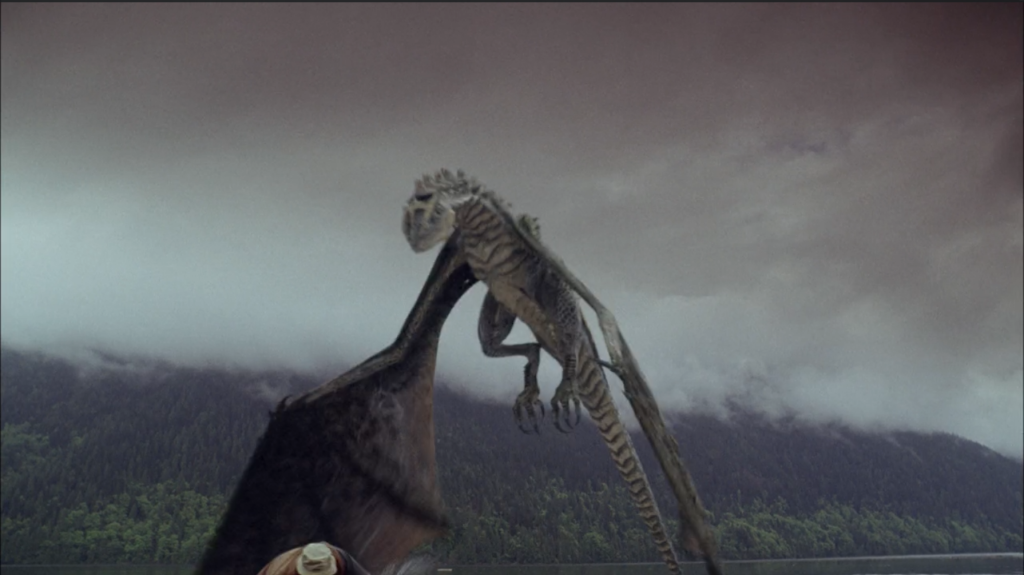 A photograph from tje film Wyvern depicting the titular dragon. It has two wings and two legs and is landing in front of a fisherman.