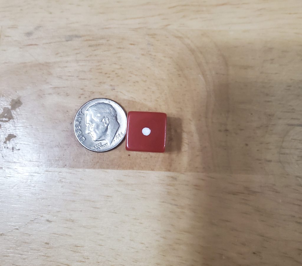 A die compared to the size of a dime. The die is slightly smaller.