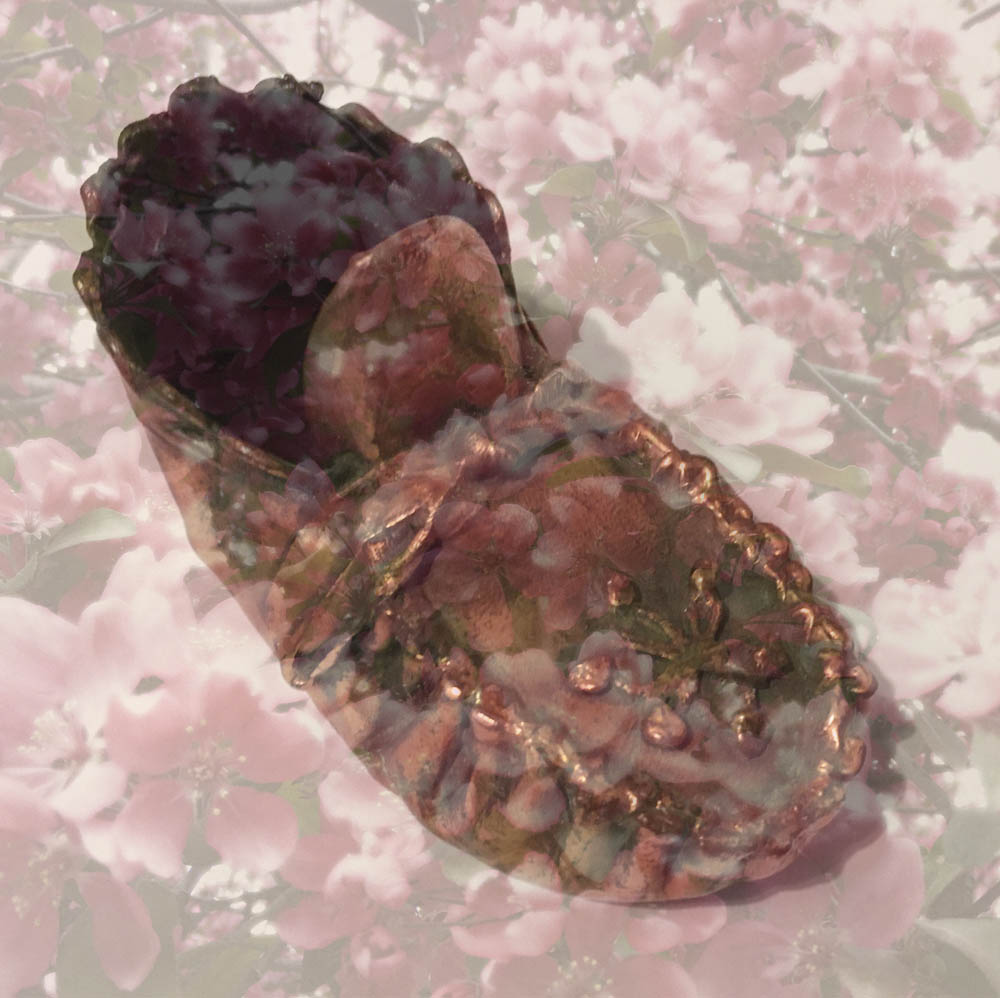 A bronzed baby bootie fading away into a field of luminous pink flowers