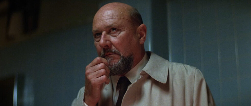 Dr Loomis stands looking concerned with his hand on his face.