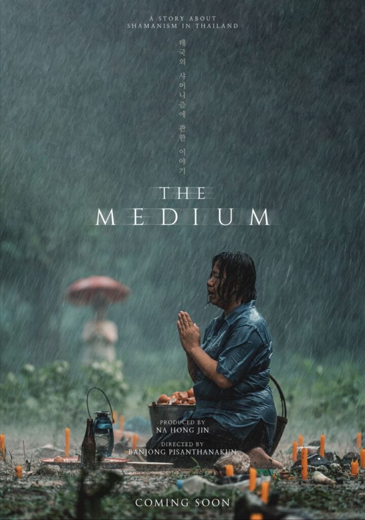 The Medium  horror poster - a woman praying on a grave near some mushrooms as rain comes down.