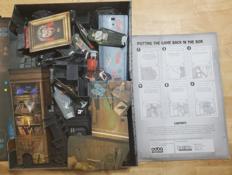 The Ghost Castle box open next to the rulebook which is open the the section "Putting the Game Back in the Box"
