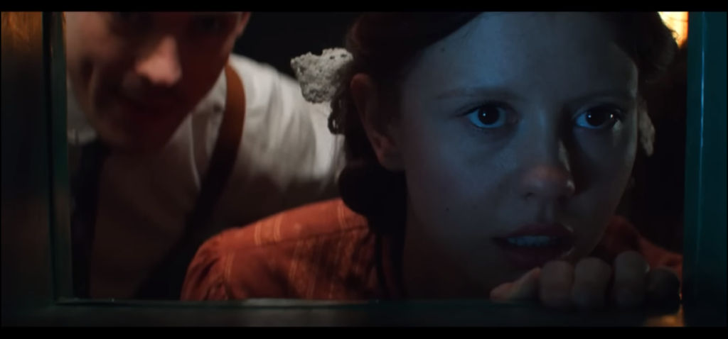 Screenshot from 'Pearl' of Mia Goth as Pearl and David Corenswet as The Projectionist watching a movie.
