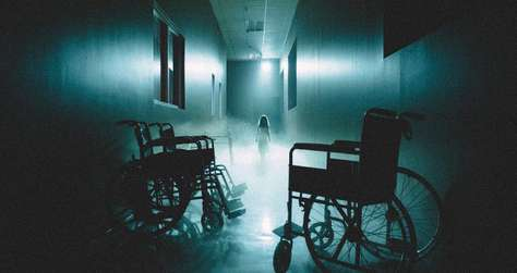 Haunted Hospital S4 shows a spooky corridor with two wheel chairs and a phantom coming to get you!