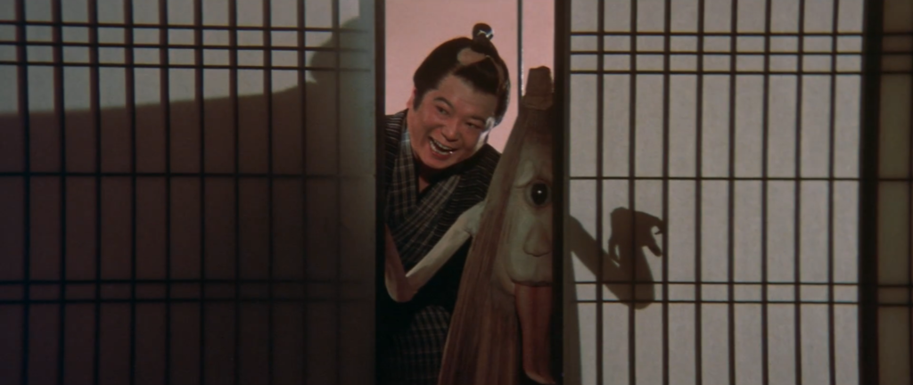Shinkichi (Rookie Shin-ichi) peers from behind a shutter with a kasa-obake, a possessed umbrella yokai