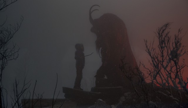 In one of Krampus more awe-striking shots, Max stands face to face with the Yuletide demon; his crooked branch gripped in hand at the ready. Krampus, draped in his festive robes, looms over his caller, as black and grey clouds painted with hues of red from the faint glow of flames envelop the night sky. 