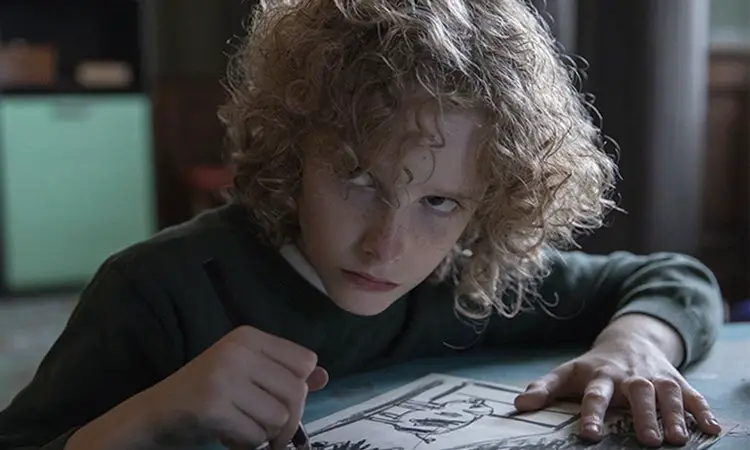 Elijah Wolf as Manny, drawing a picture with a sinister glare