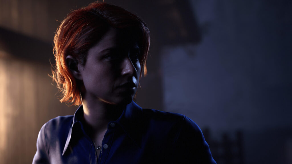 A woman with red hair is looking ahead, looking concerned, half her face is buried in a shadow.