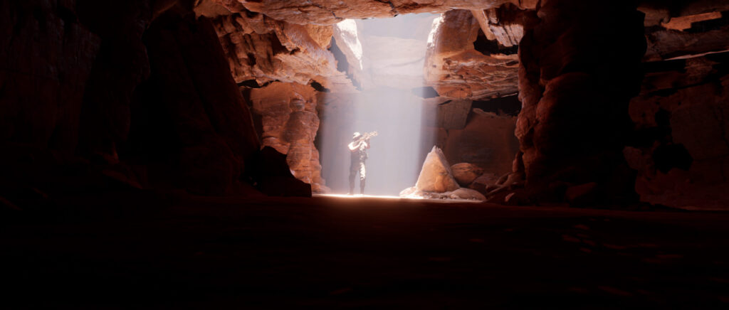 A man is walking under rays of sun holding a gun, he is in an underground cave.