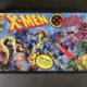 Nine people fight each other in a vintage comic book style with the words X-Men Under Siege across the top in comic font