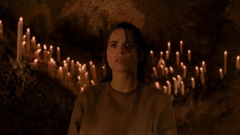 A woman in a cave waits, surrounded by candles.