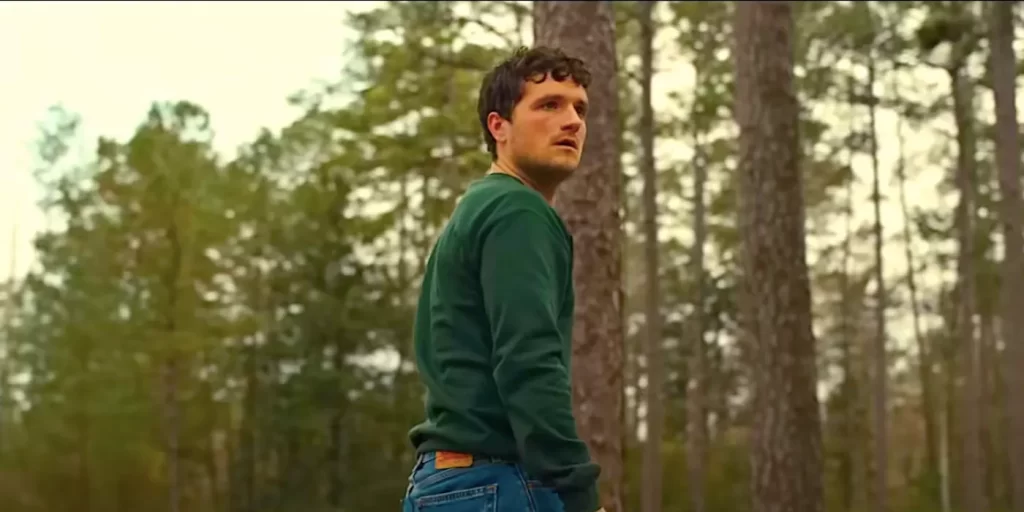 Josh Hutcherson looks back, surrounded by a forest with a dreamy look.