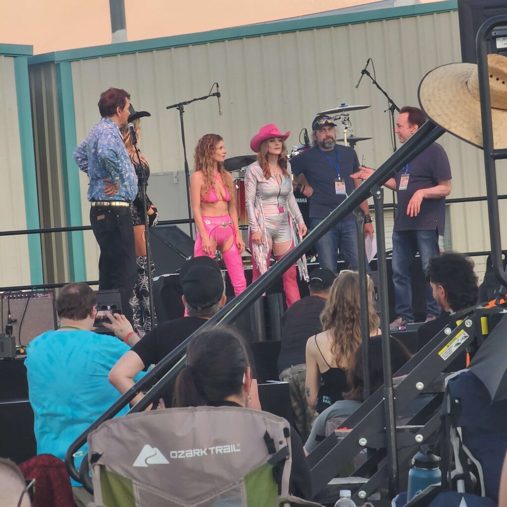 A photo of the cast and crew of Barbie & Kendra Crash Joe Bob’s Drive-In Jamboree on stage with Joe Bob and Darcy.