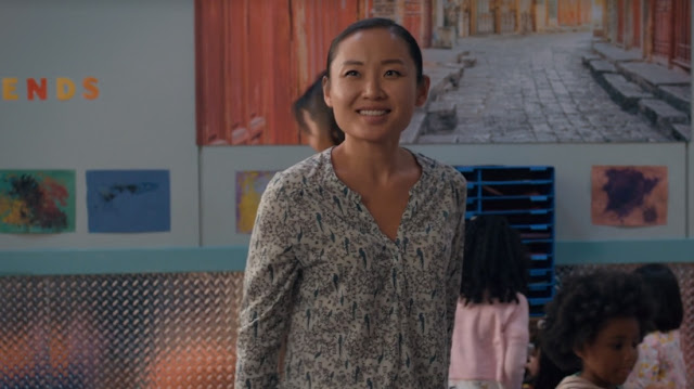 A woman smiles at the viewer, set in a youth classroom.