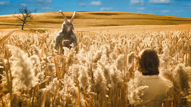 Among a scenic wheat field, a woman (Kristen) walks away from the viewer. Ahead of her is a demon and behind him is a barren tree