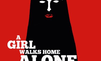 A red background reveals a woman in black. Her face is white and lips are red. The title reads "A Girl Walks Home Alone At Night"