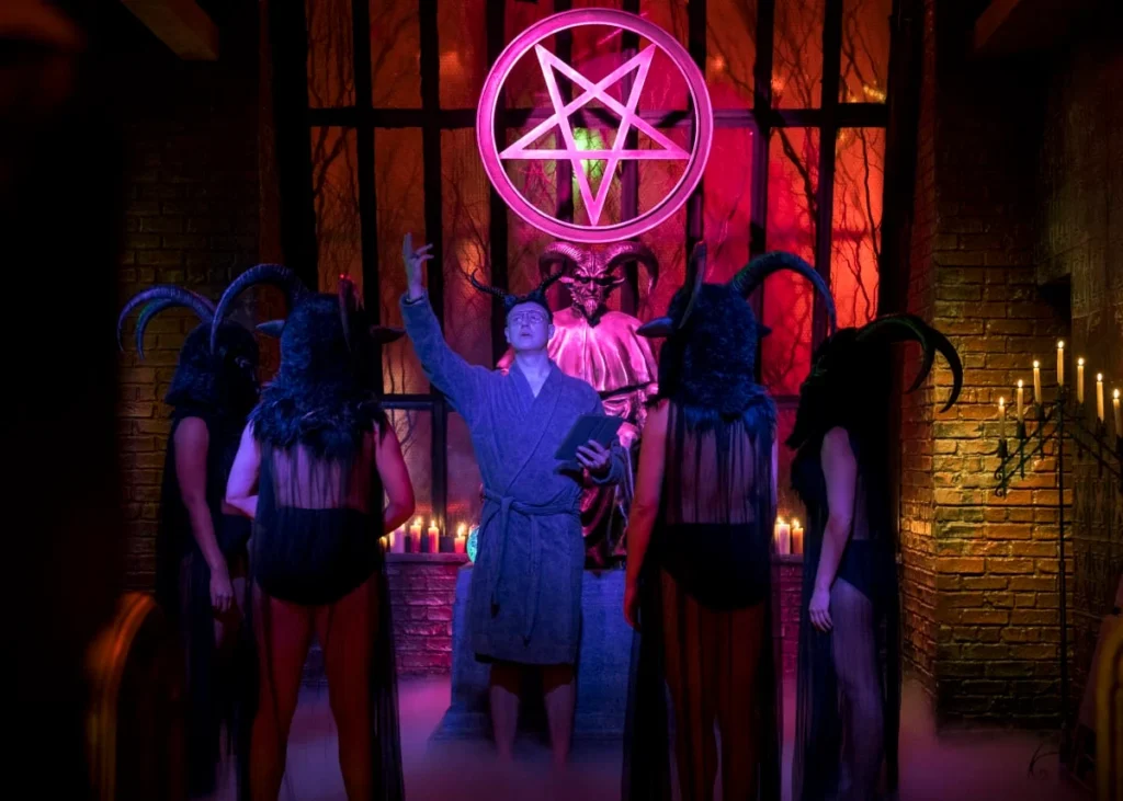 Masked and robed figures congregate under a satanic star.