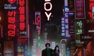 Among colorful neon signs light up both sides of the poster. Between reads Oldboy, written vertically. A man and woman walk underneath it all, looking lost and small.