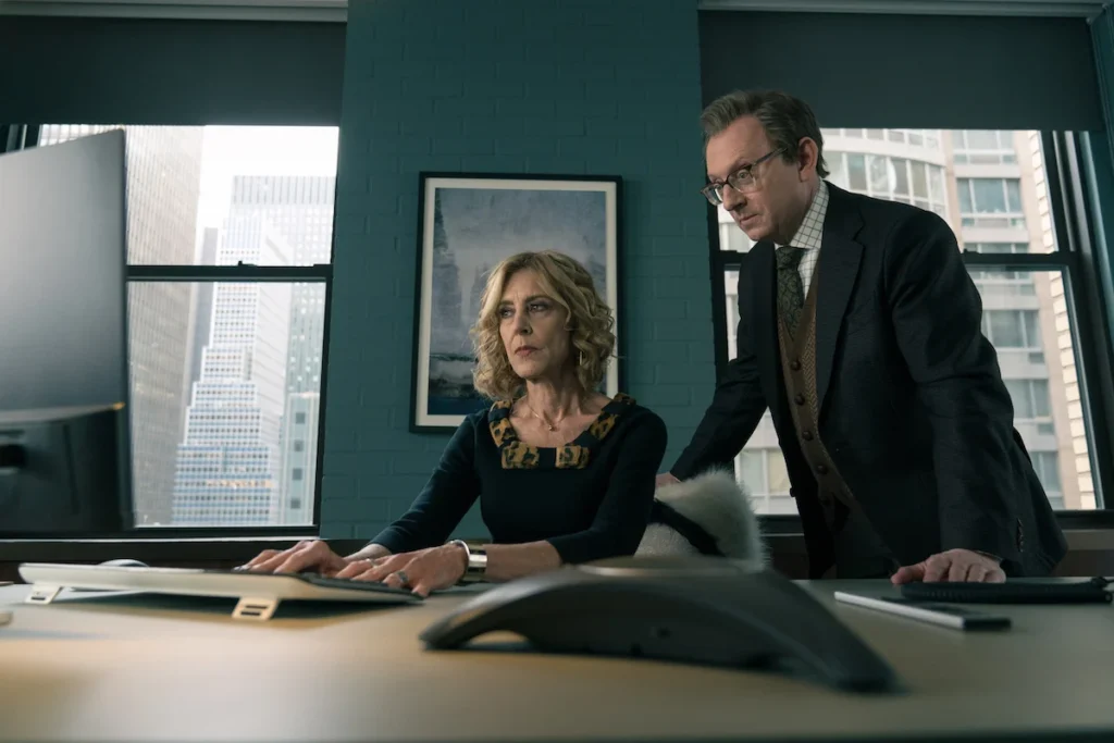 A man looms over a woman's shoulder, both looking at a computer screen. The screen is hidden from the audience