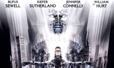 Dark City reads on a white background in silver text. A face forms from the city. Below it, a man stands in a crucified position.