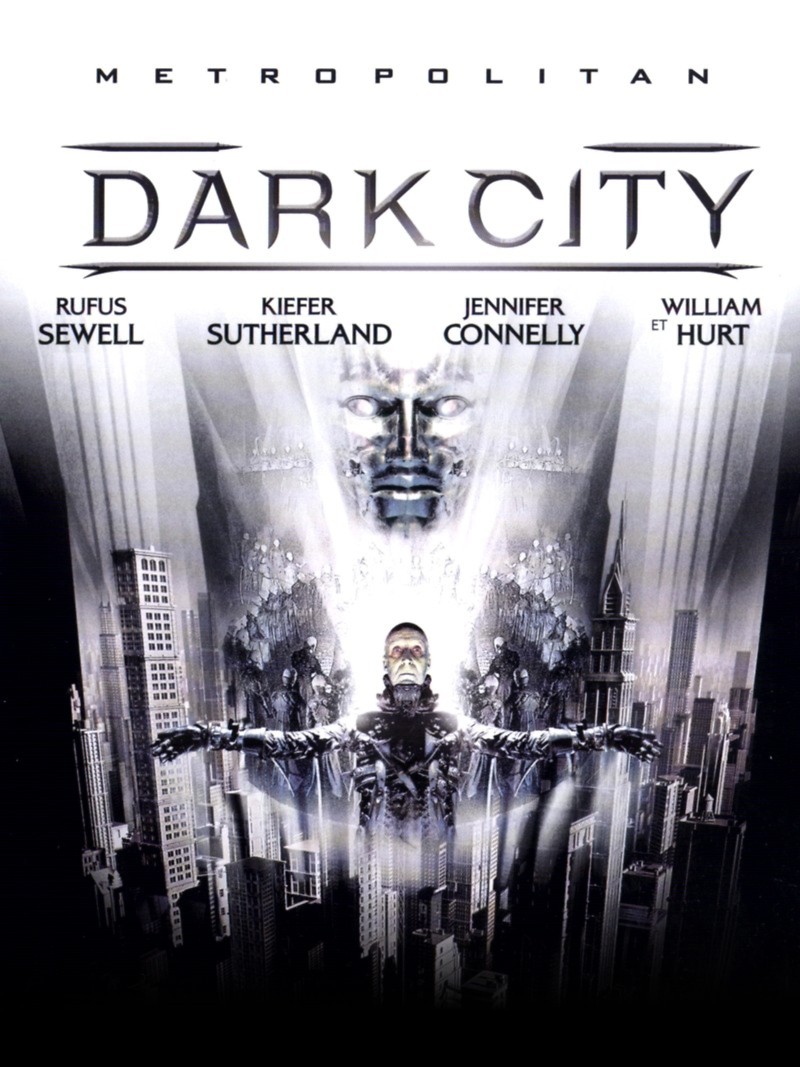 Dark City reads on a white background in silver text. A face forms from the city. Below it, a man stands in a crucified position.