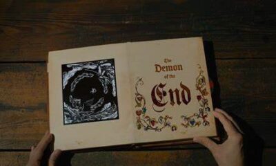 Hands open a popup book. The right side reads "The Demon of the End" and the left shows a vast void with creatures swarming around it.